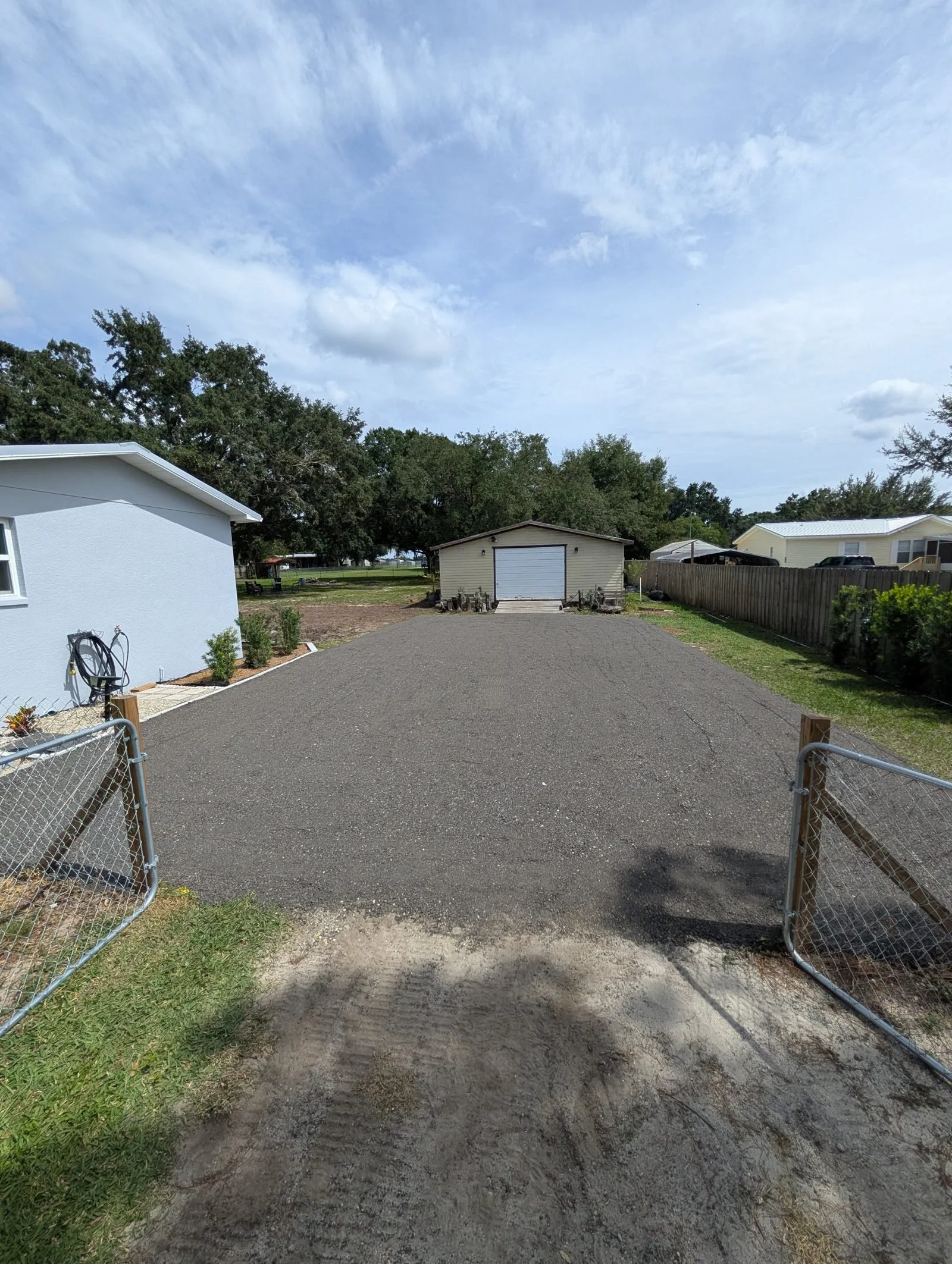 Finished crushed-asphalt driveway leading to the same garage after Polk Services installed it.