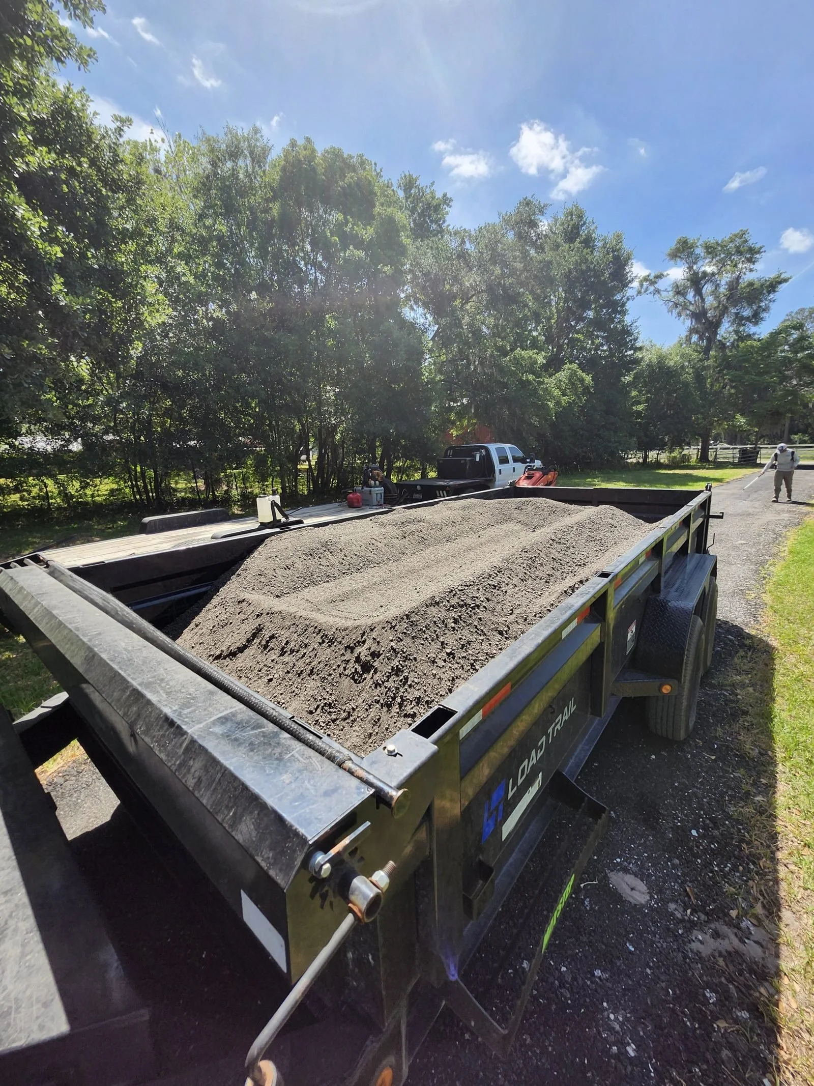 Polk Services heavy junk hauling in Lakeland, FL — the skid steer loading concrete and construction debris into a dump trailer.