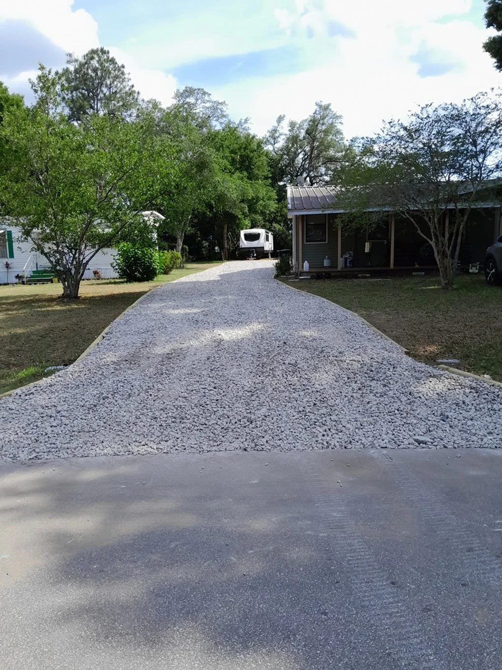 Polk Services gravel driveway installation in Lakeland, FL — the Kubota SCL1000 spreading crushed-asphalt milling.