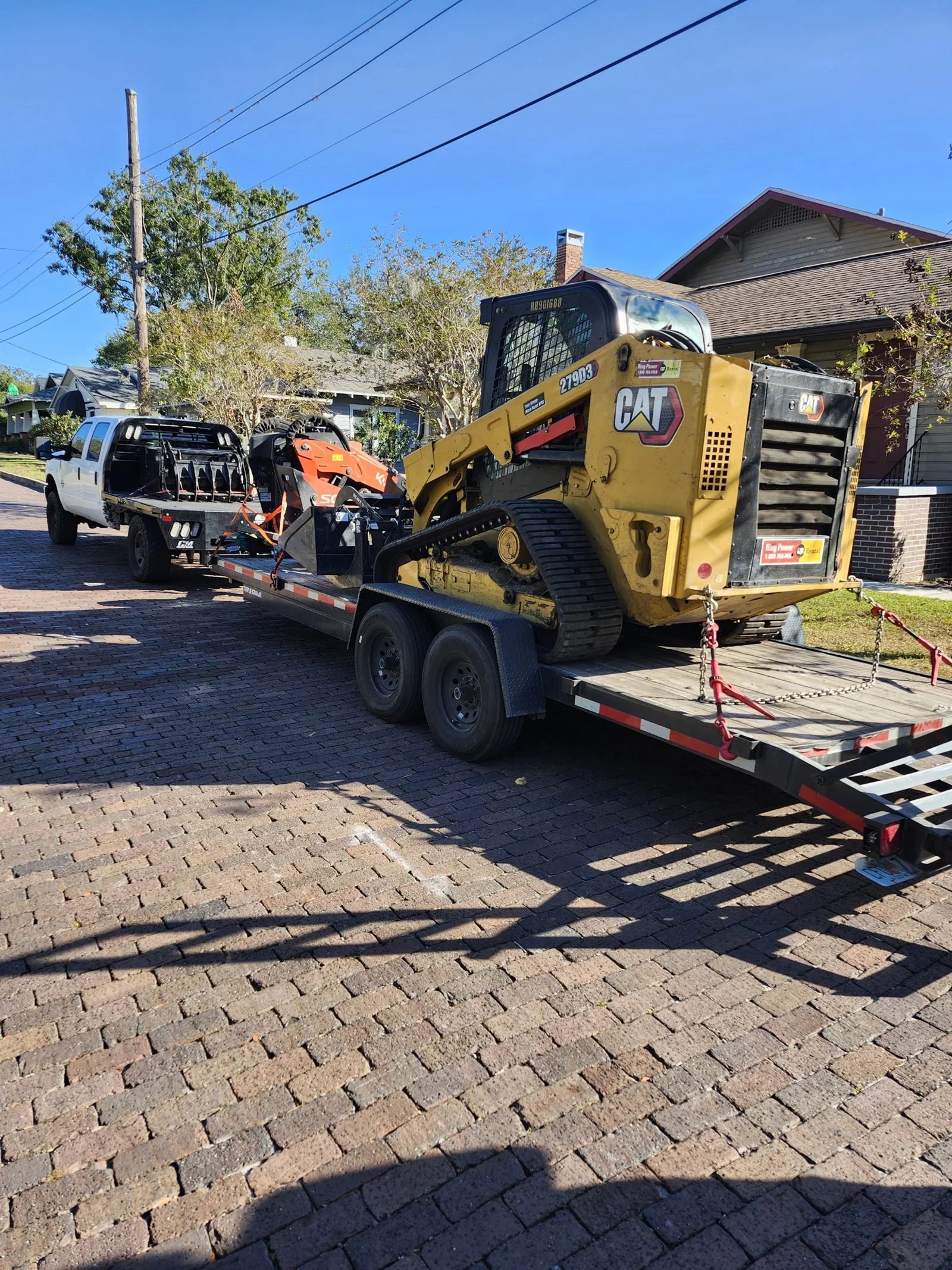 The Polk Services Kubota SCL1000 working with the bucket attachment on a residential lot.