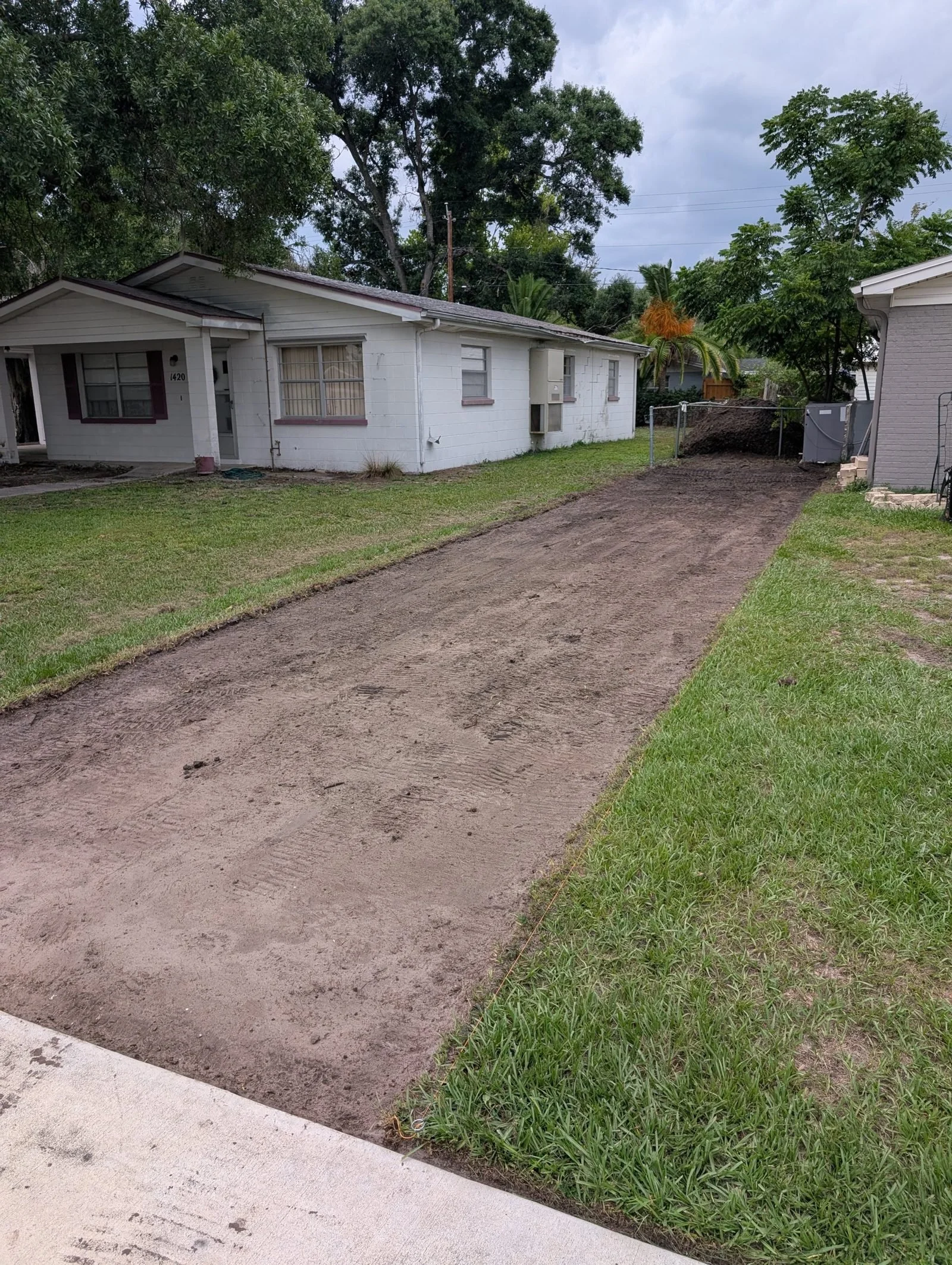 Bare dirt drive before the Polk Services crushed-asphalt install.