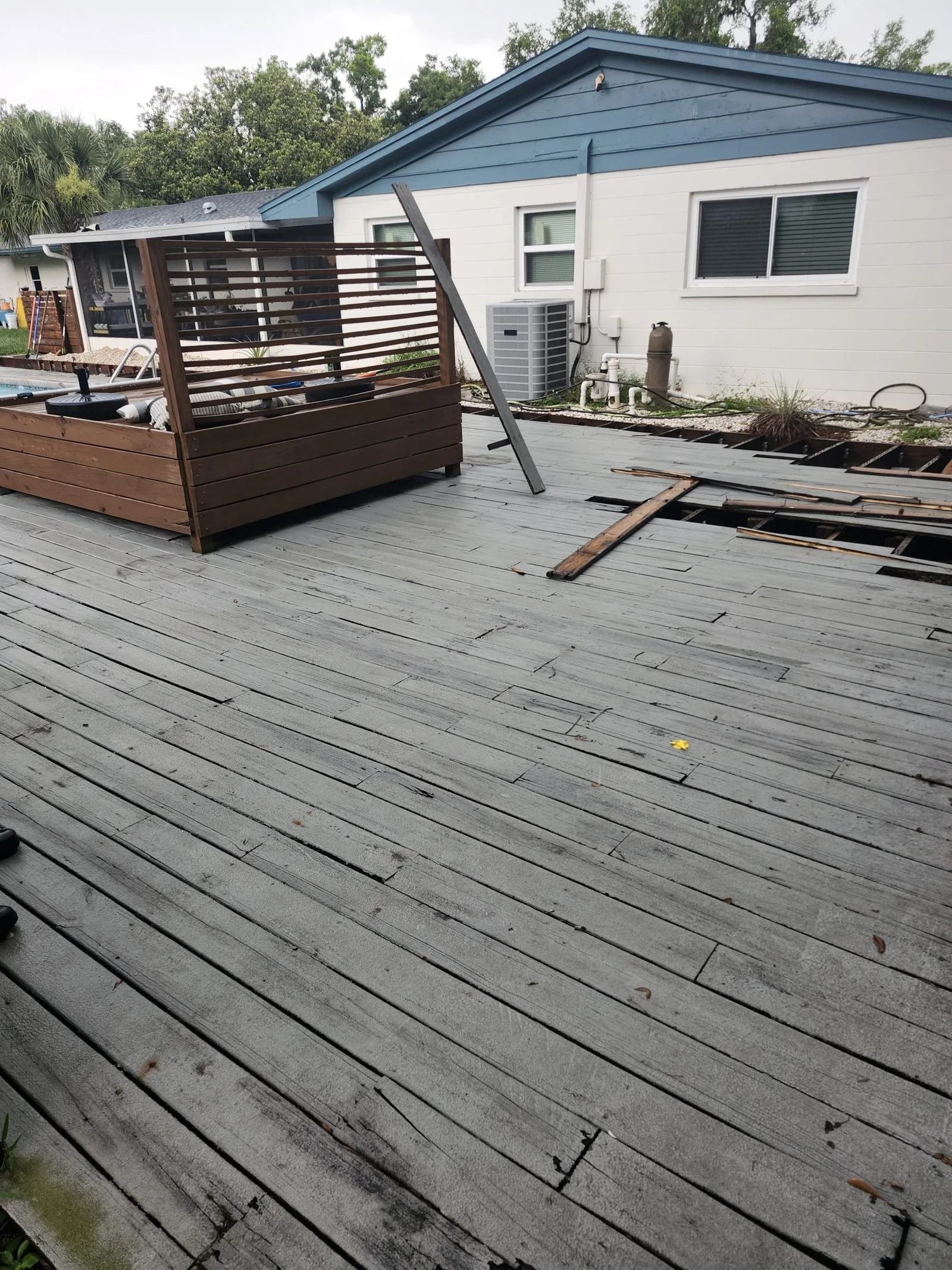 Worn wood deck with loose boards before Polk Services removed it.