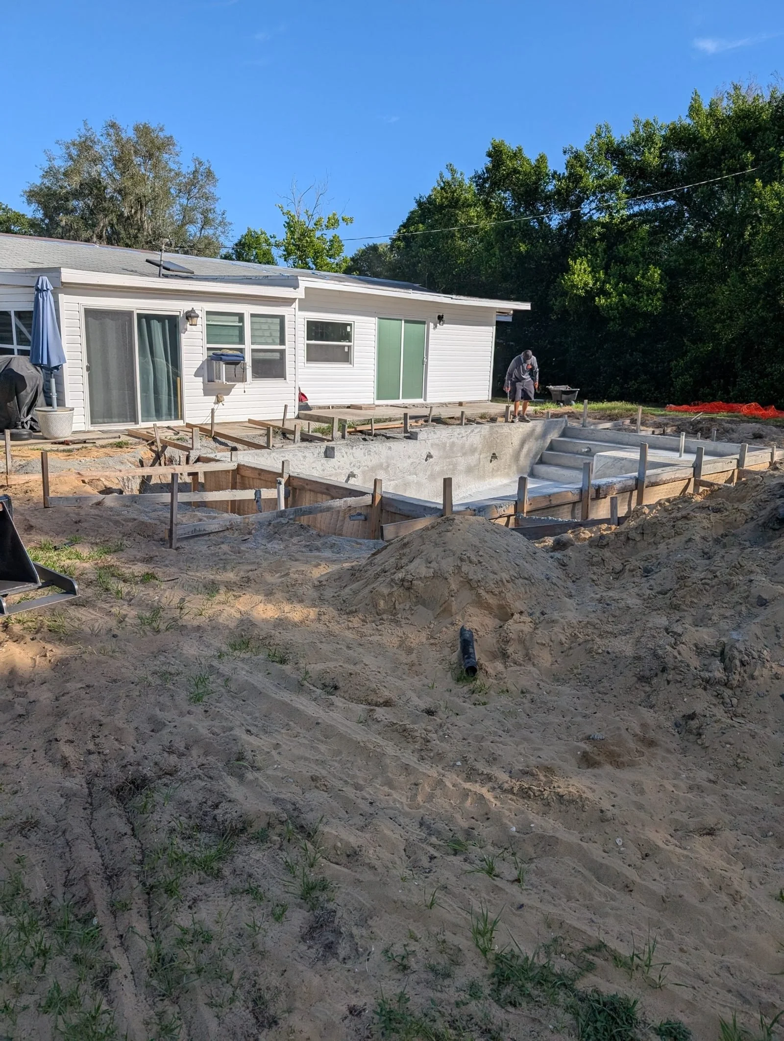 Rough dirt and old forms around the pool before Polk Services grading.