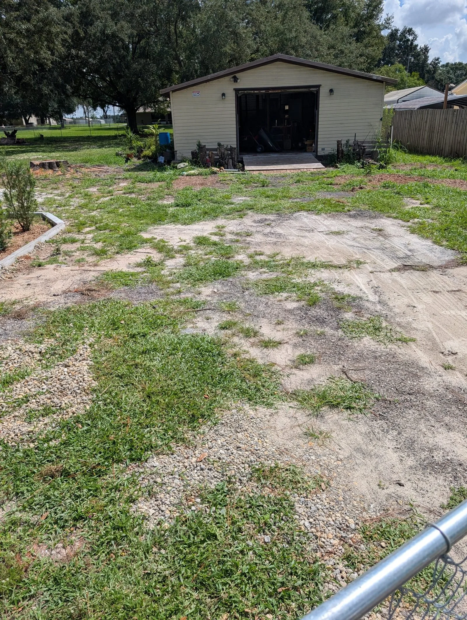 Bare, patchy sand yard before a Polk Services crushed-asphalt driveway install.