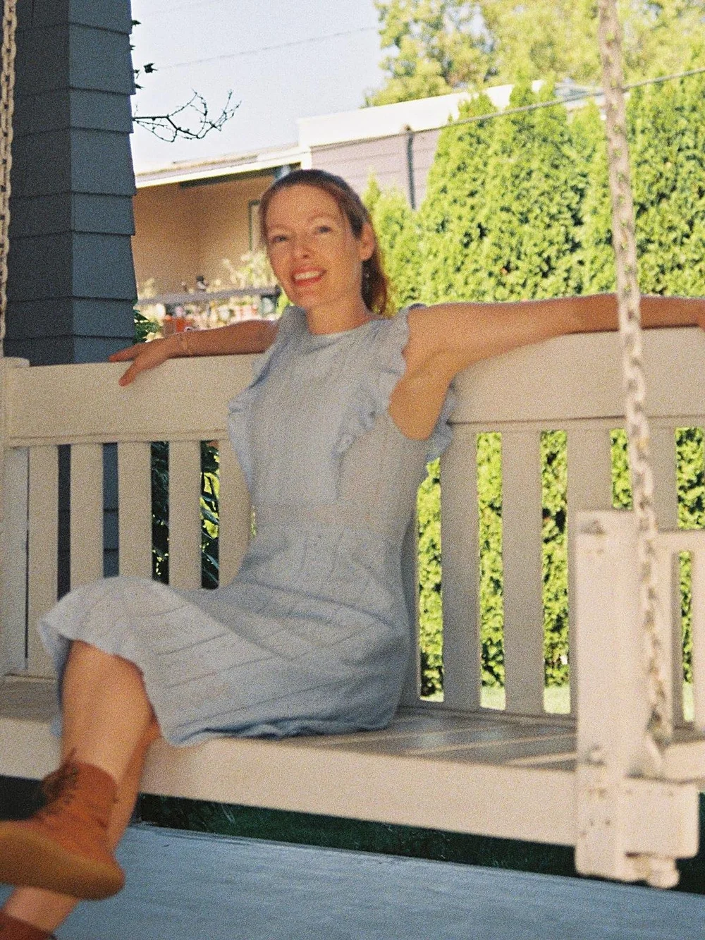 Dr. Abigail Stephens relaxing and smiling on the white porch swing of the Stewart House in Springfield, Oregon.