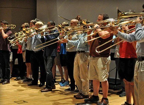A trombone section of students playing together in a rehearsal hall