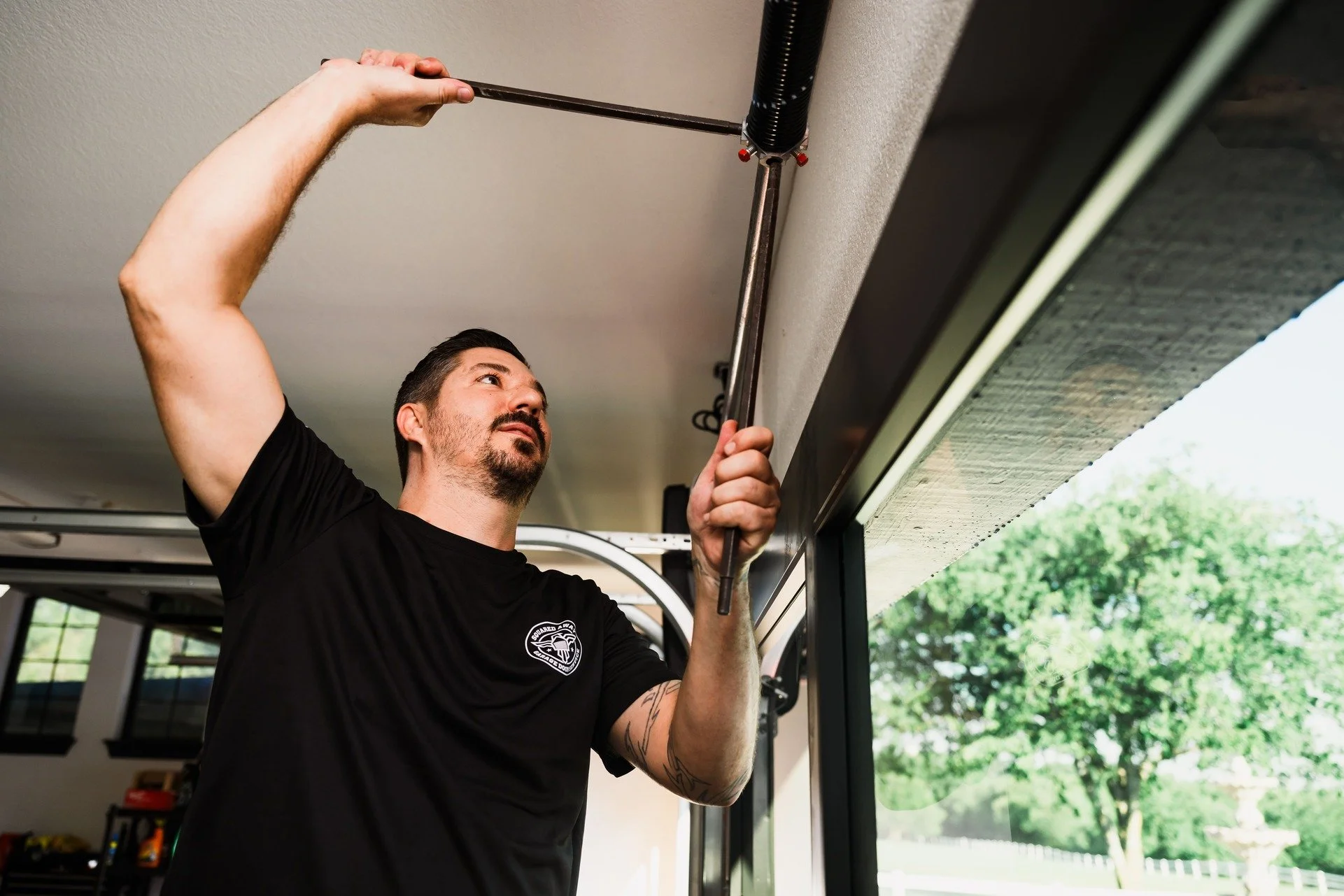 a technician weighing a wide double garage door before sizing a torsion spring on a Brushy Creek home in Brushy Creek, TX by Squared Away Garage Door Service