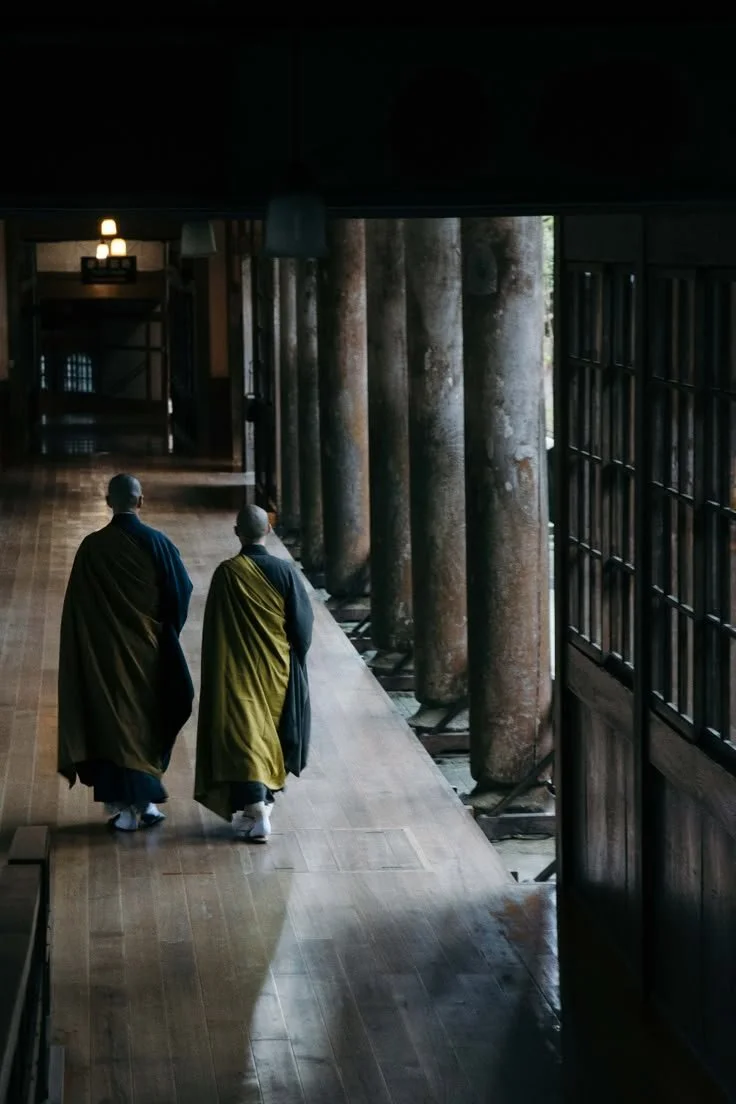 Two monks walking a temple corridor in Japan