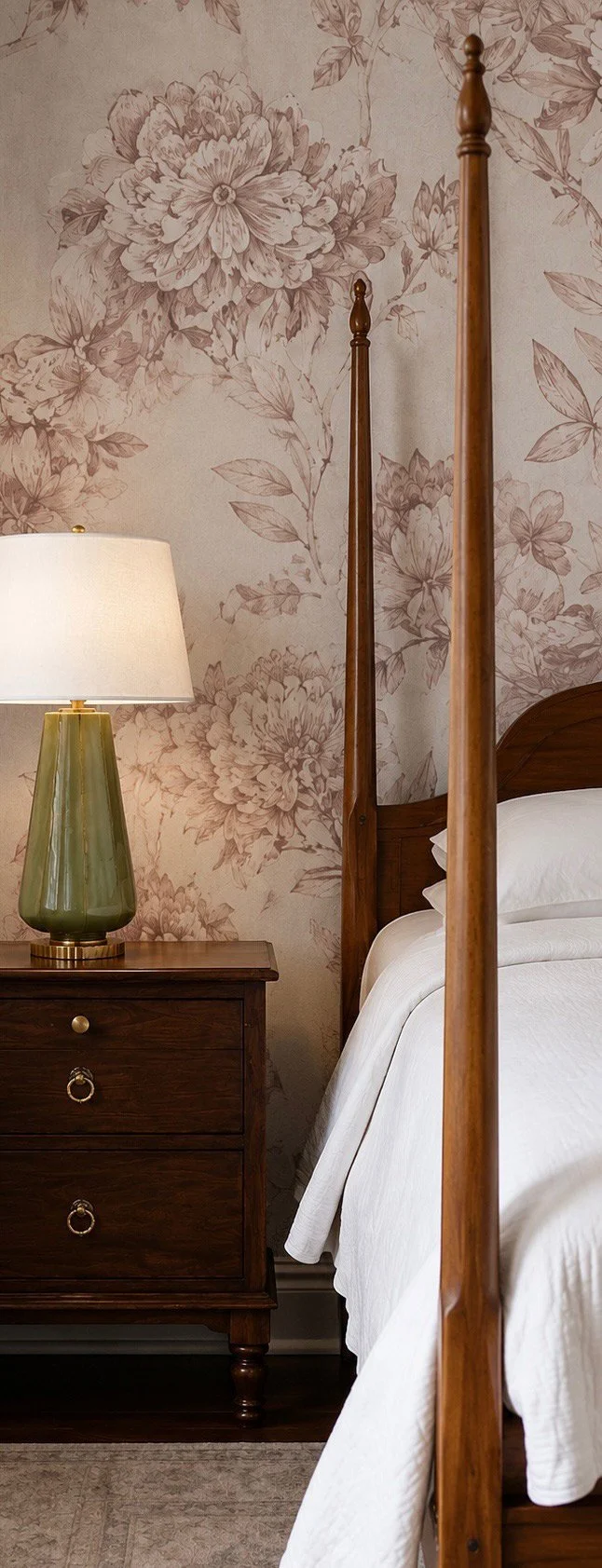 Four-poster bed, green lamp, and floral wallpaper