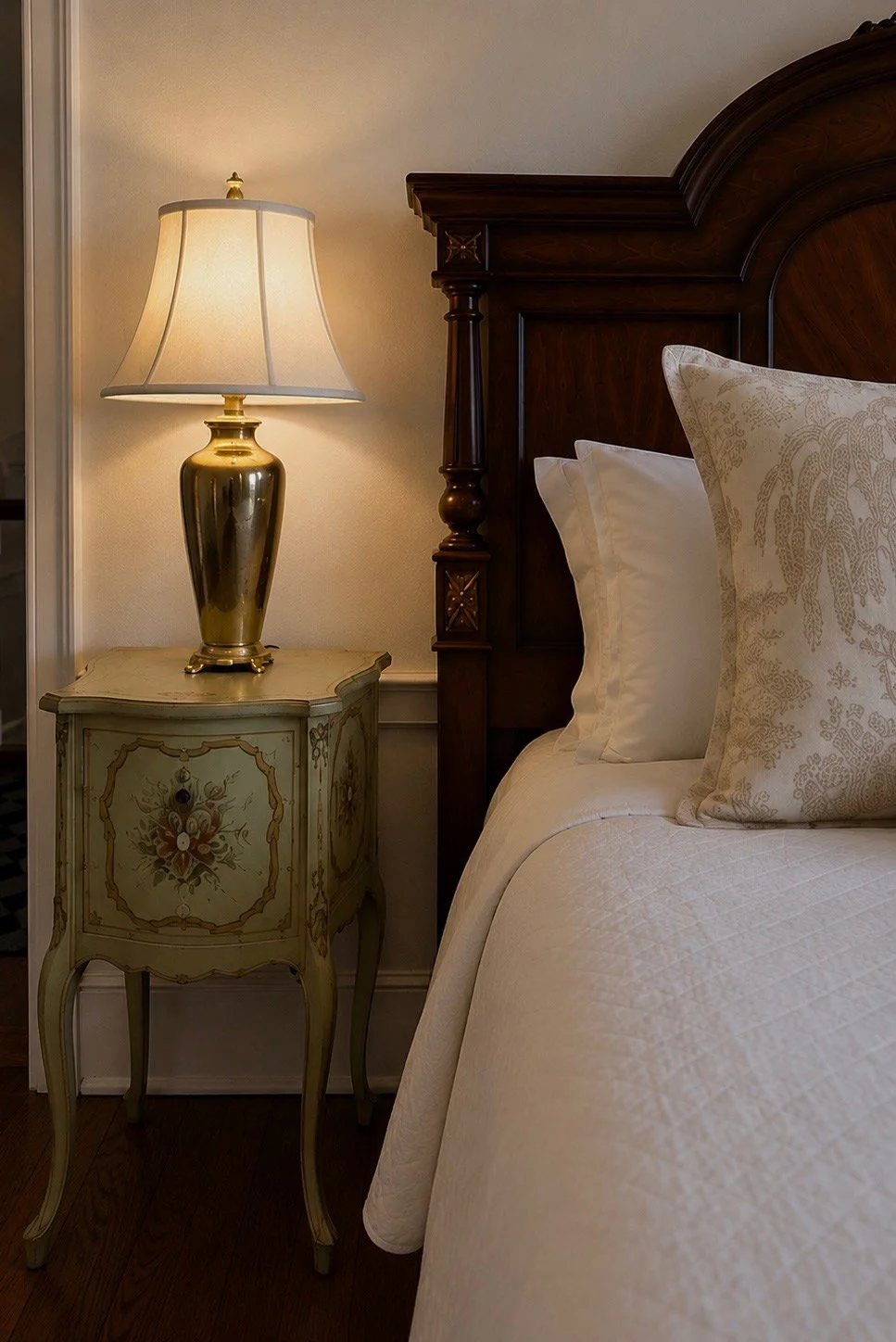 Brass bedside lamp beside a carved dark-wood bed