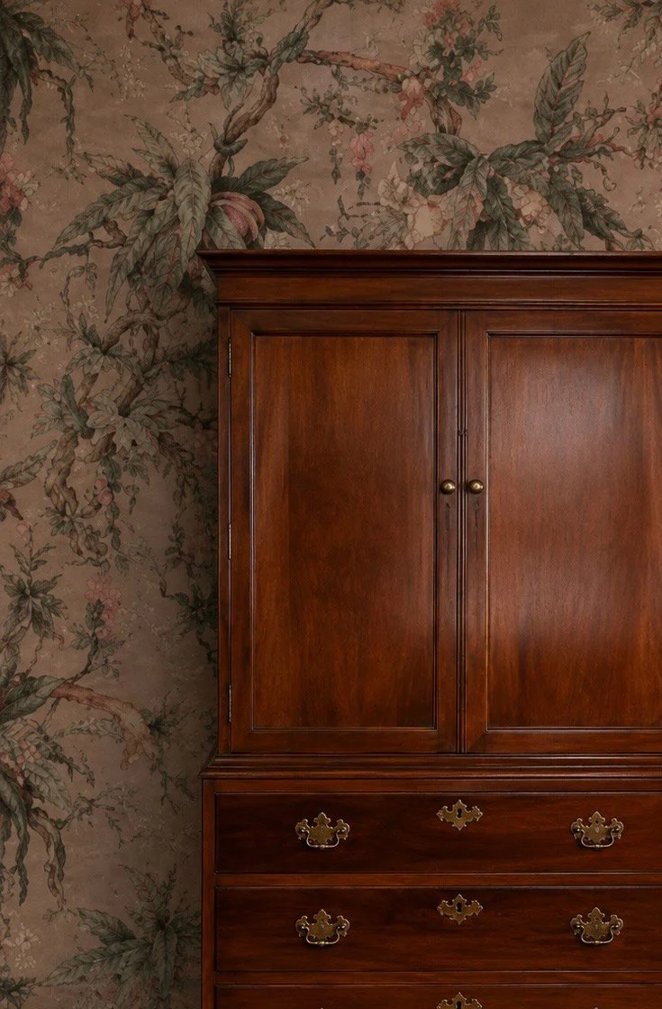 Dark-wood dresser against richly patterned wallpaper