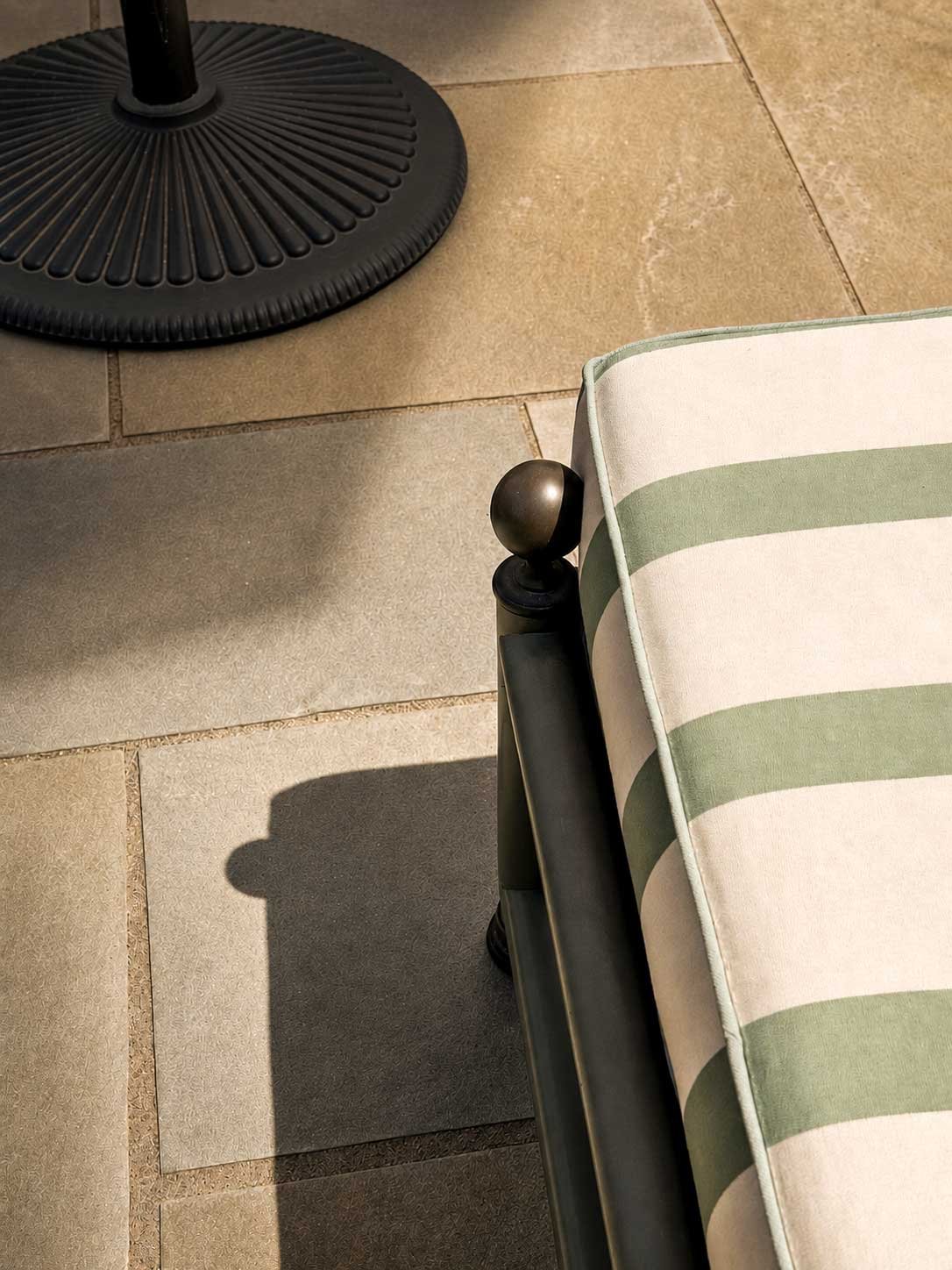 A striped courtyard cushion in warm afternoon light at The Buxton Inn