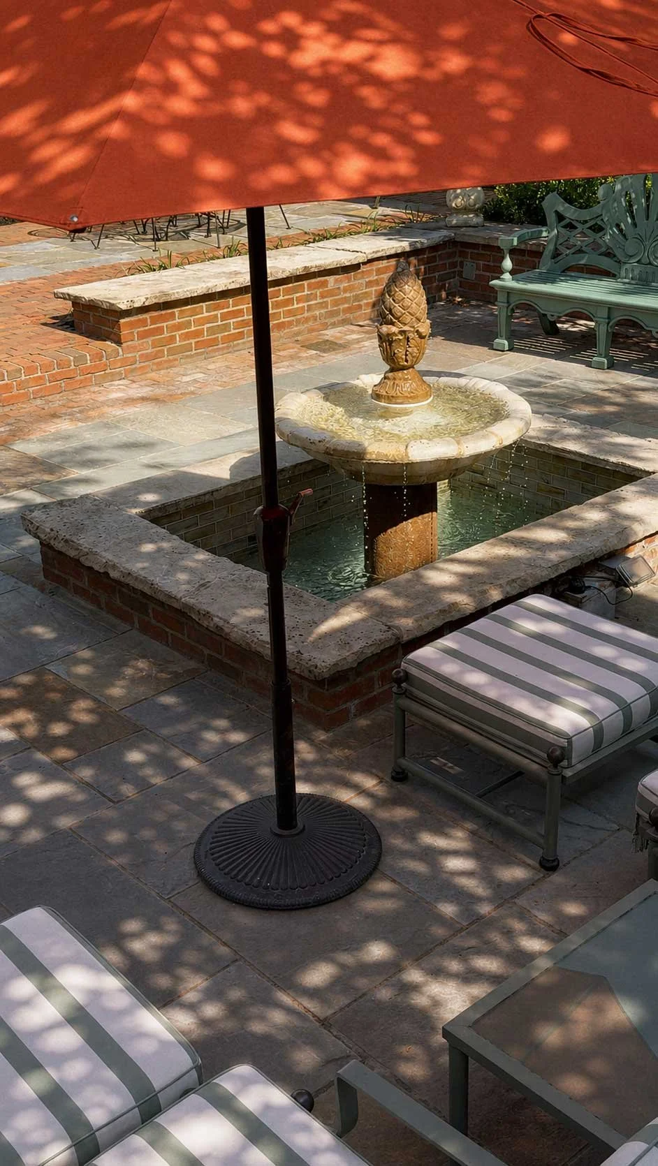 An elevated view of the Buxton Inn courtyard with fountain, striped seating, brickwork, and umbrella
