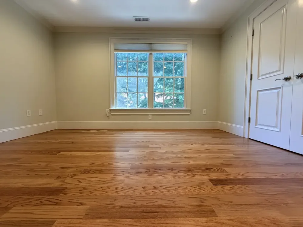 Completed red oak flooring in the Wellesley bedroom with double closet doors