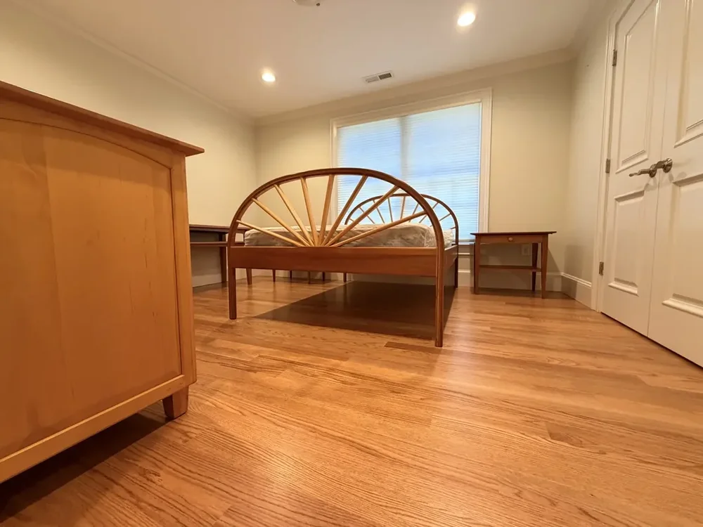 Completed red oak flooring in the Wellesley bedroom with double closet doors with furniture returned