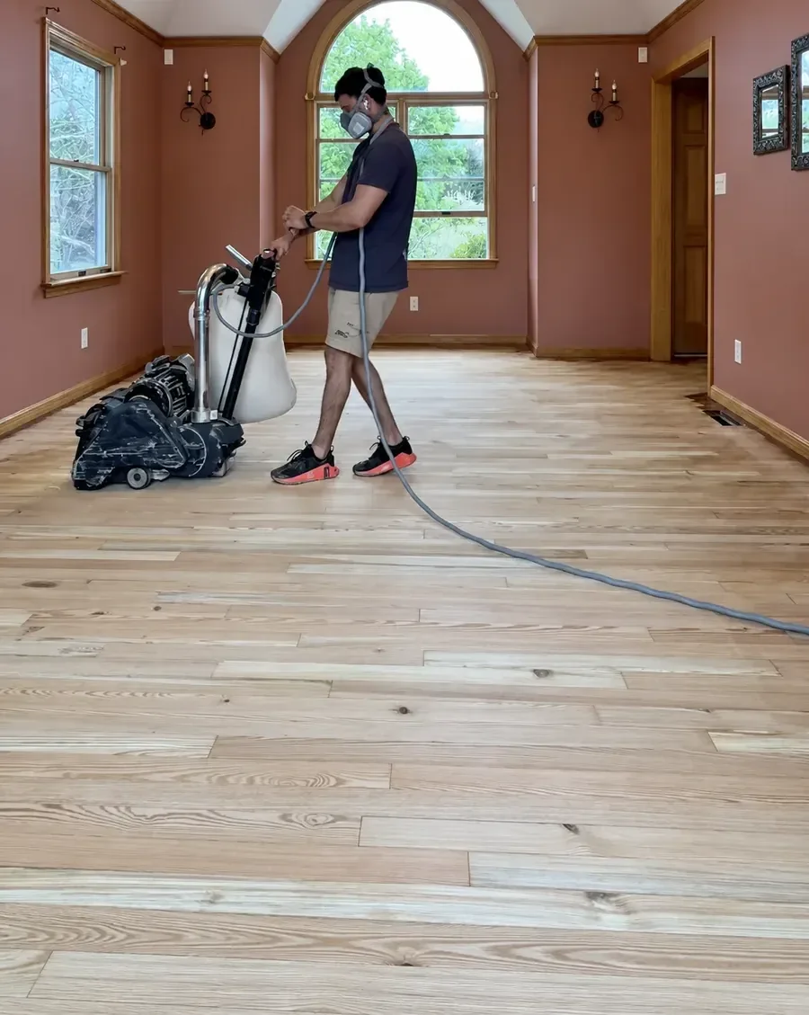 John operating a floor sander in a room with an arched window