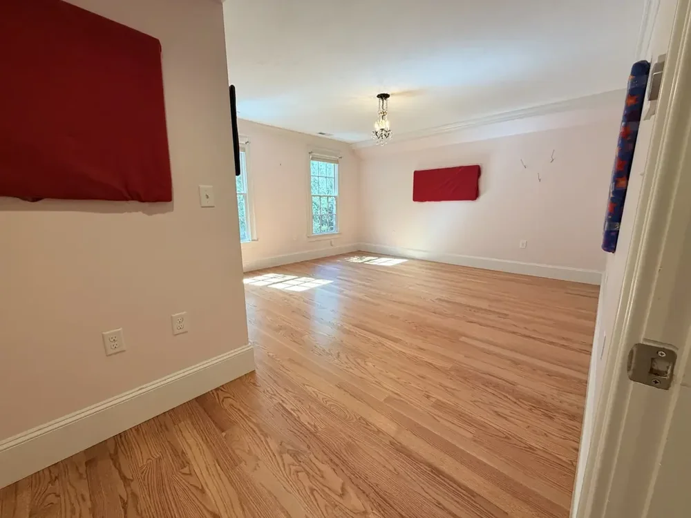 Completed red oak flooring in the Wellesley bedroom with red wall panels