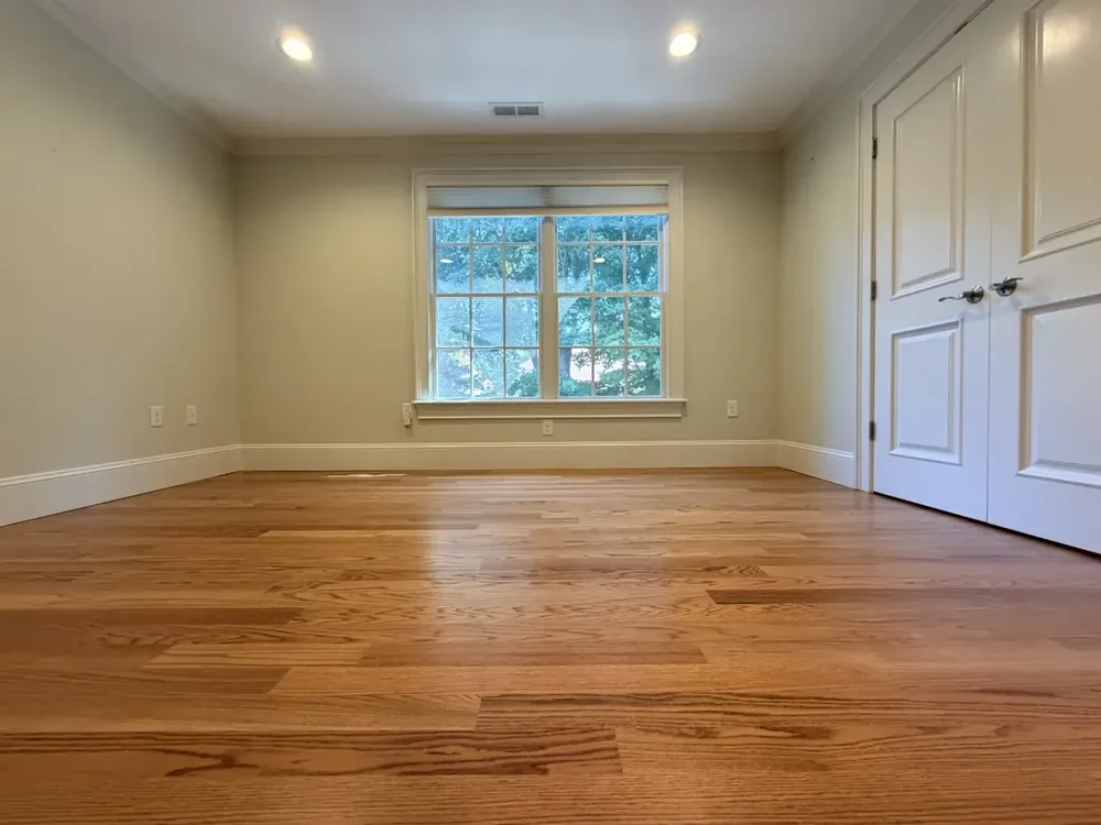Completed red oak flooring in the Wellesley bedroom with double closet doors