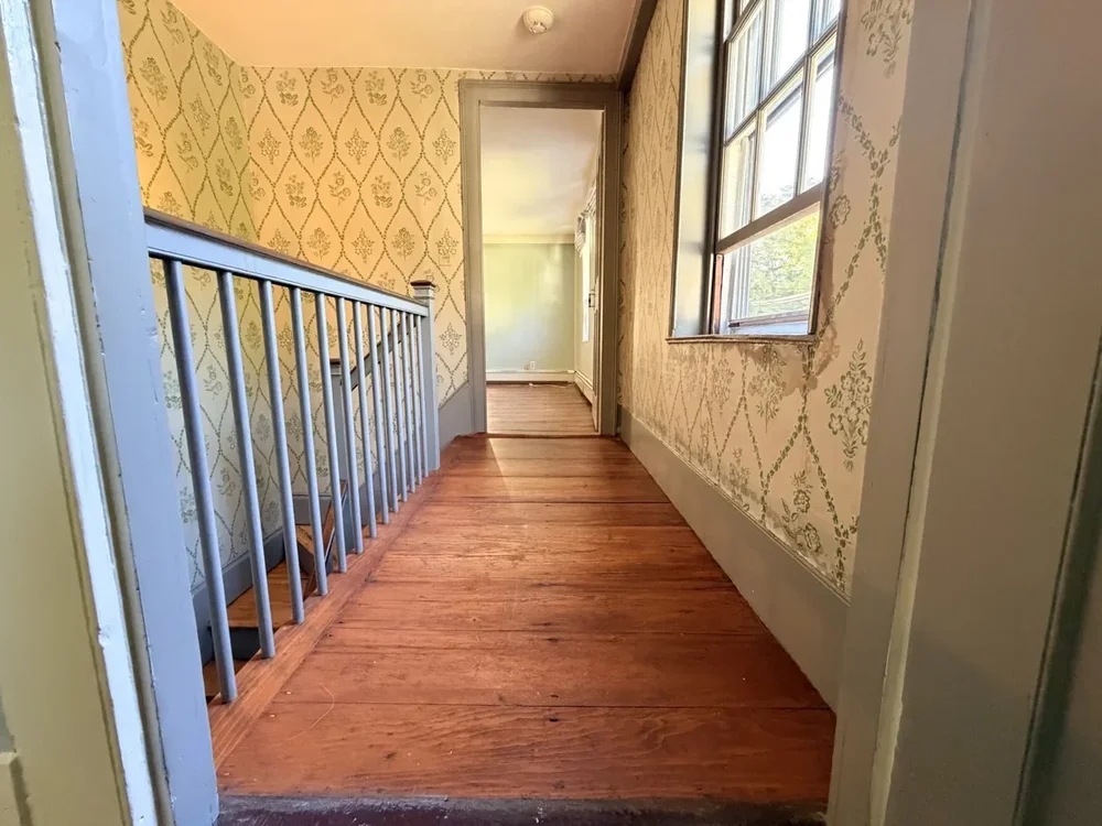 Wallpapered landing toward doorway before refinishing