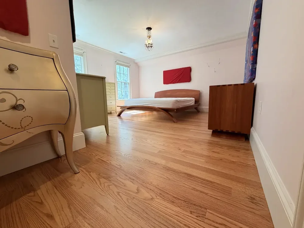 Completed red oak flooring in the Wellesley bedroom with red wall panels with furniture returned