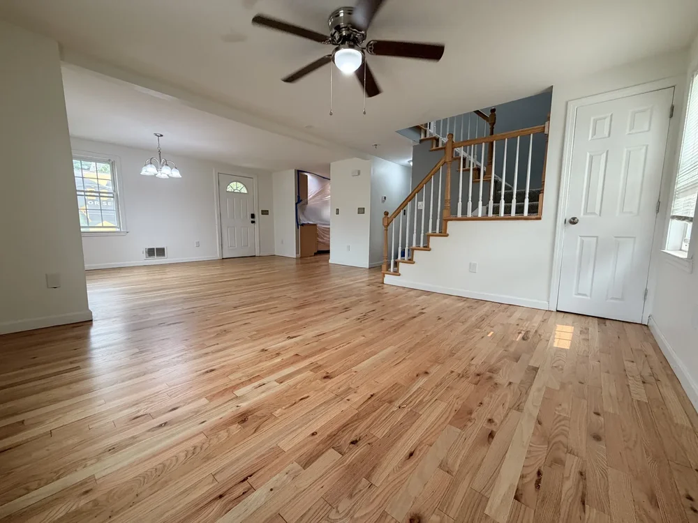 Finished hardwood floor beside a staircase and open living area