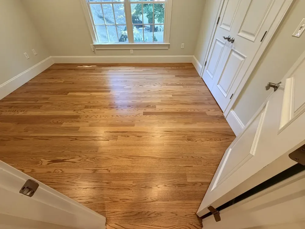 Completed red oak flooring in the Wellesley bedroom with double closet doors