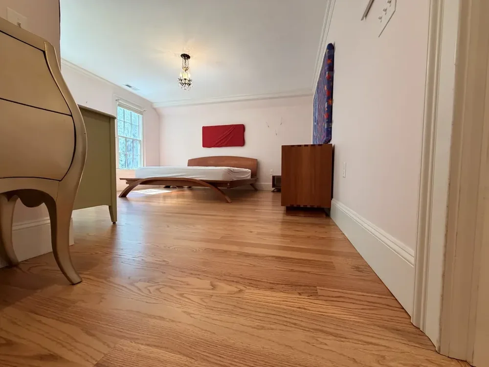 Completed red oak flooring in the Wellesley bedroom with red wall panels with furniture returned