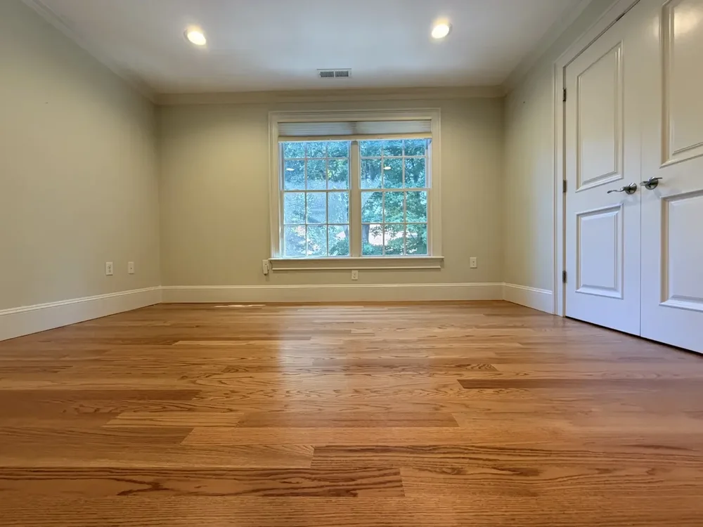 Completed red oak flooring in the Wellesley bedroom with double closet doors