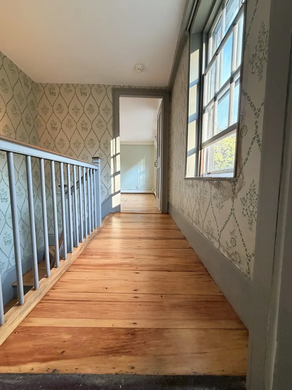 Wallpapered landing toward doorway after refinishing