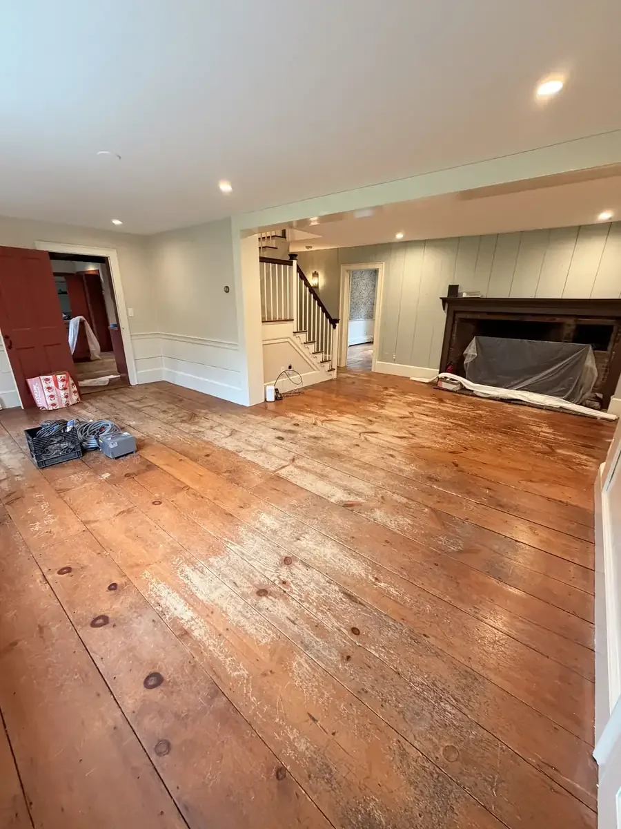 Worn wide-plank floors in the Weston fireplace room before refinishing