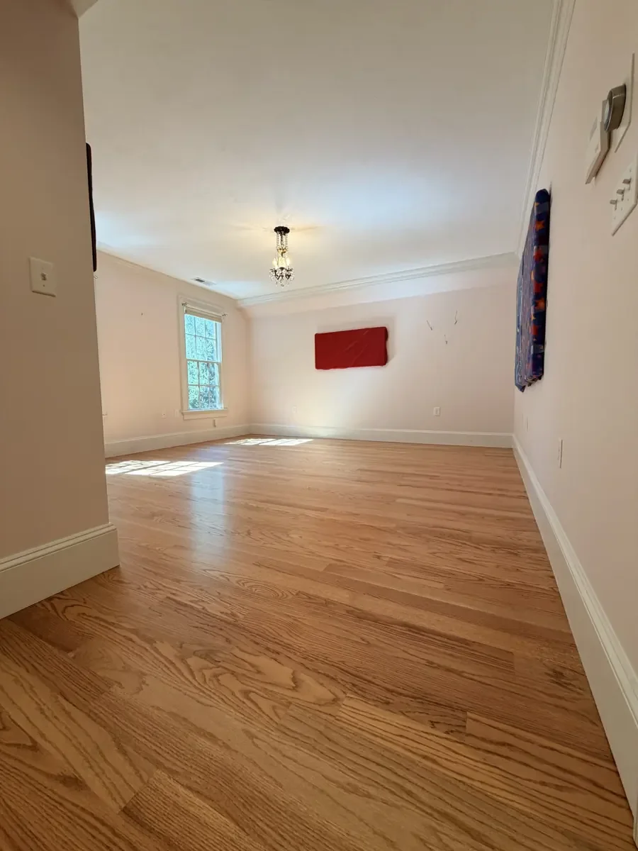 Completed red oak flooring in the Wellesley bedroom with red wall panels