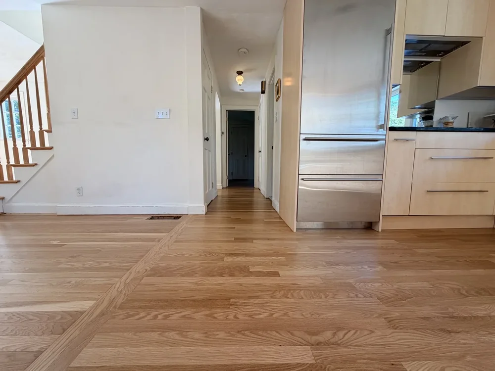 Natural wood grain continuing from the kitchen toward the hallway