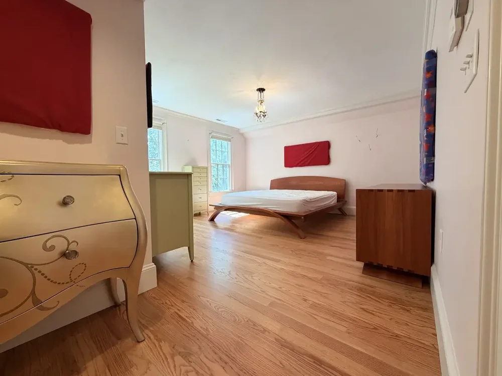 Completed red oak flooring in the Wellesley bedroom with red wall panels with furniture returned