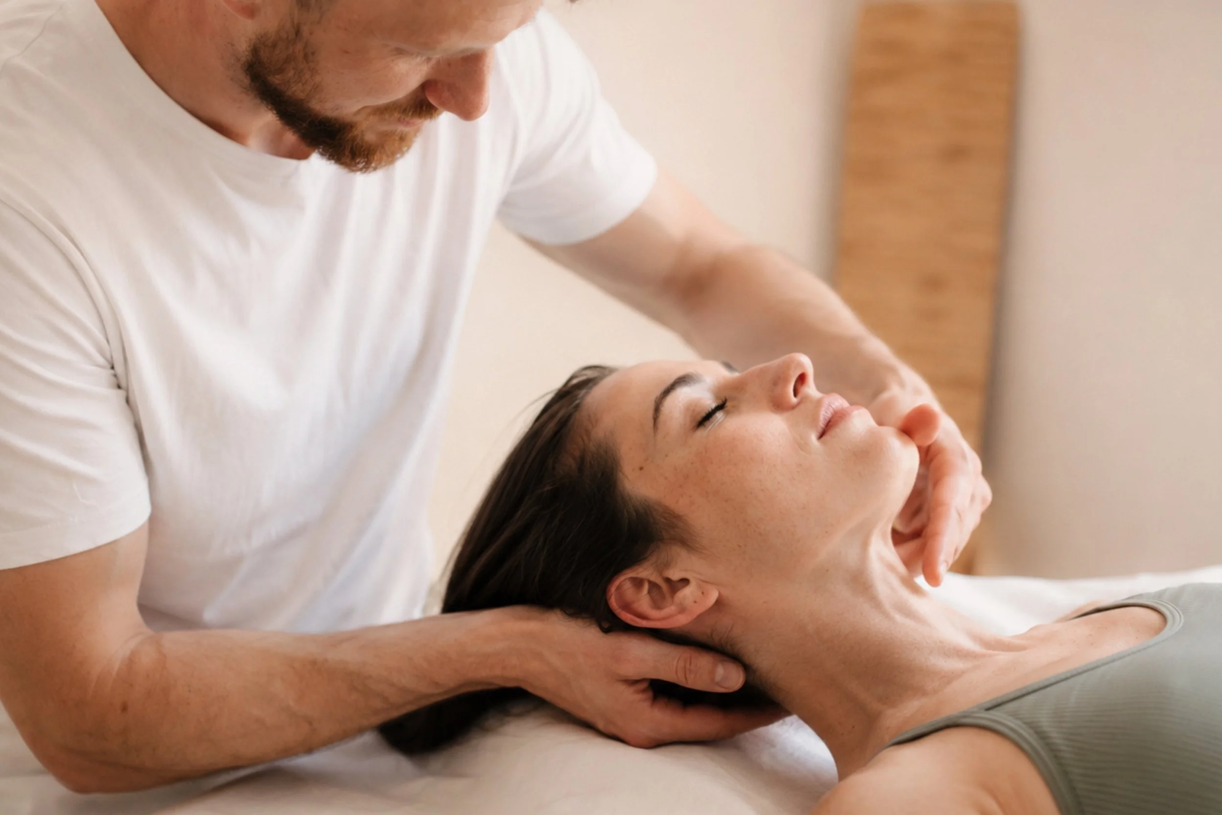 Osteopath Johannes Thies behandelt sanft Kiefer und Nacken einer Patientin in seiner Praxis in Darmstadt.
