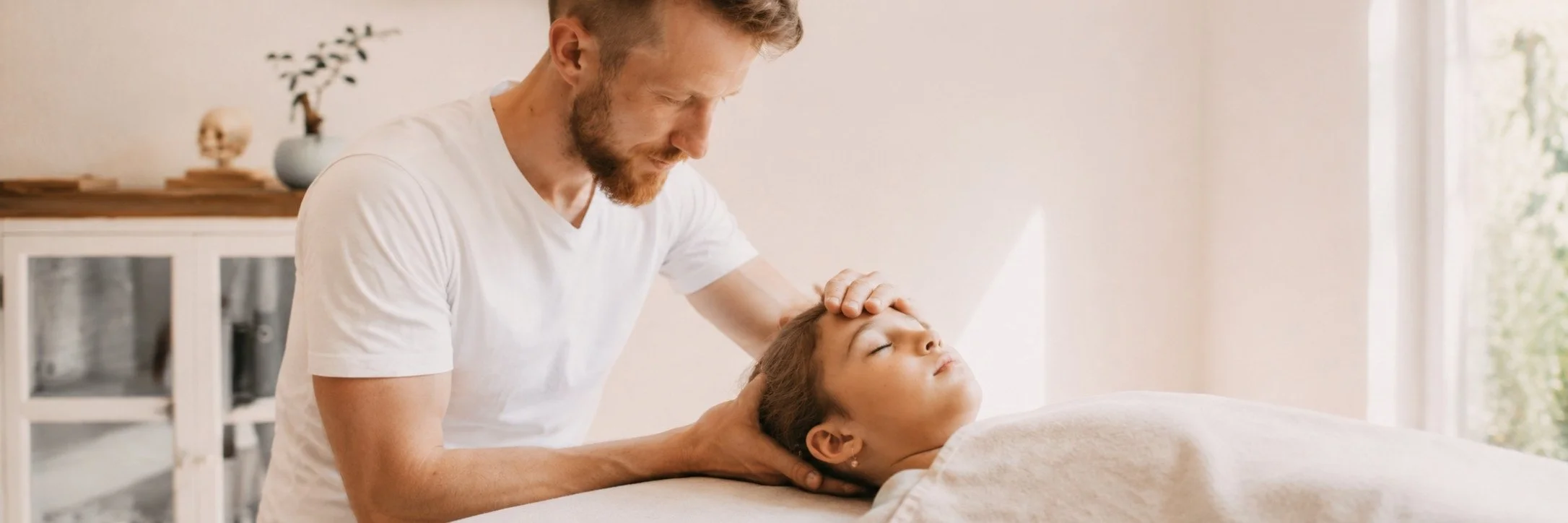 Osteopath Johannes Thies behandelt sanft den Kopf eines Kindes in seiner Praxis in Darmstadt.