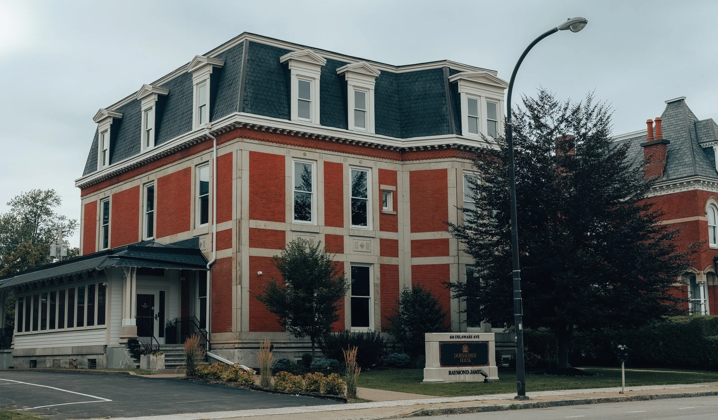 A restored brick building with a mansard roof photographed from the street
