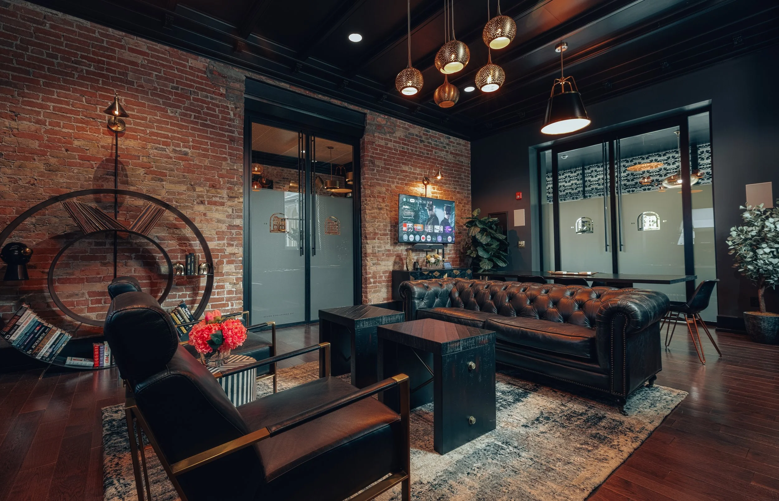 A seating area with a leather sofa below tall windows