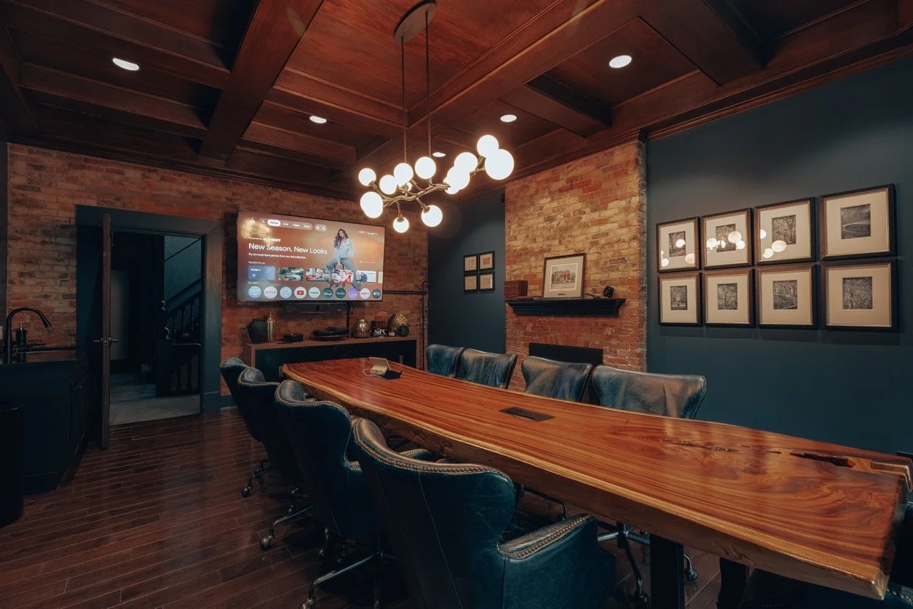 A boardroom with a live-edge wood table and globe pendant lights
