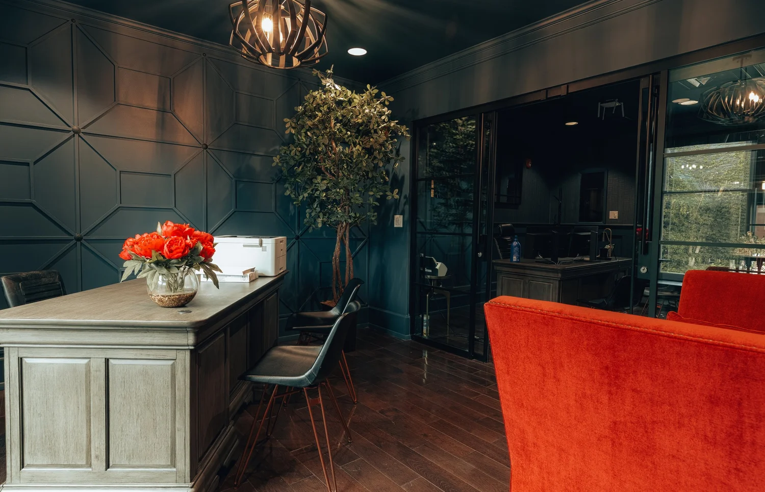 A reception counter with red flowers and a red sofa