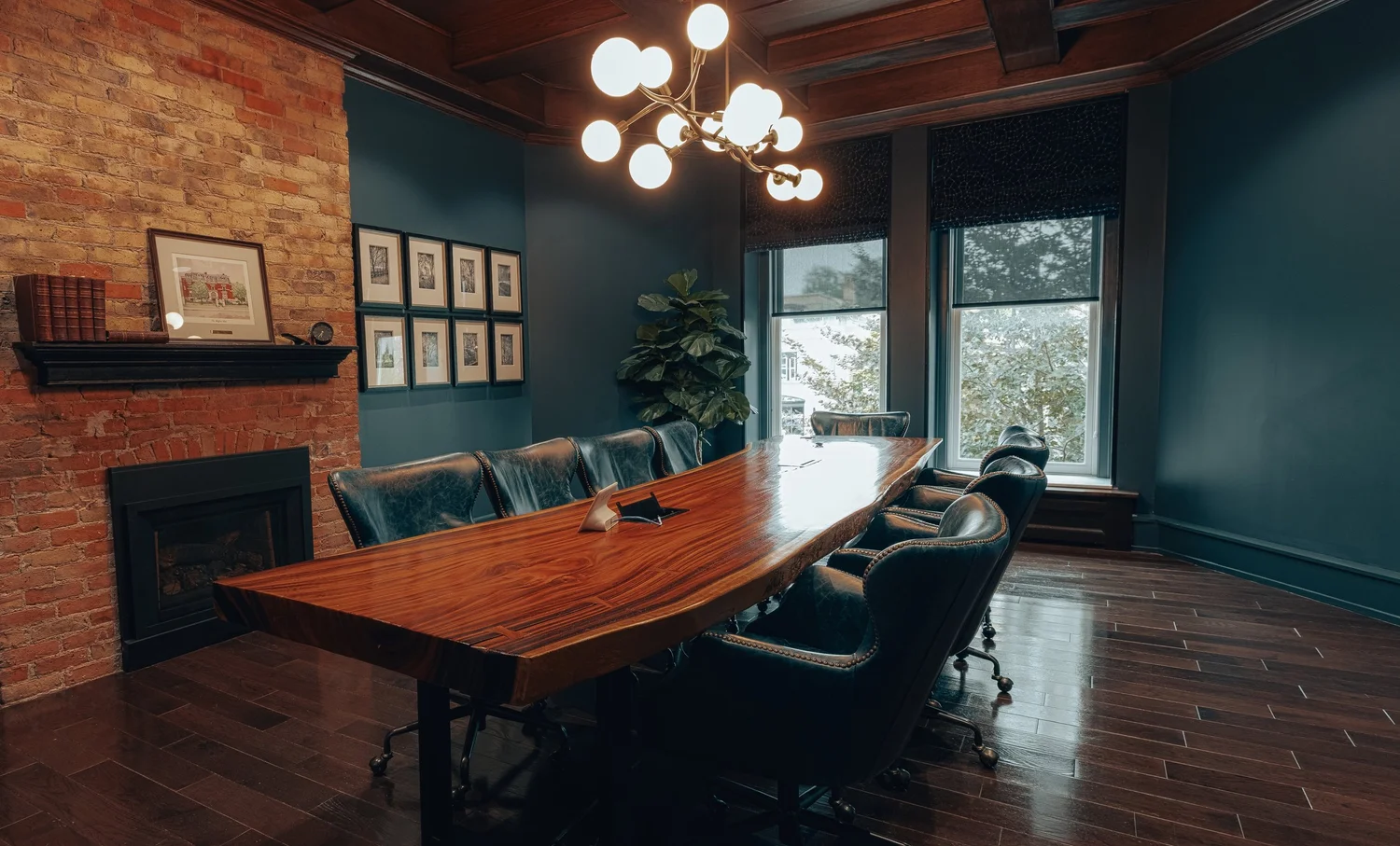 A conference table below framed prints and tall windows