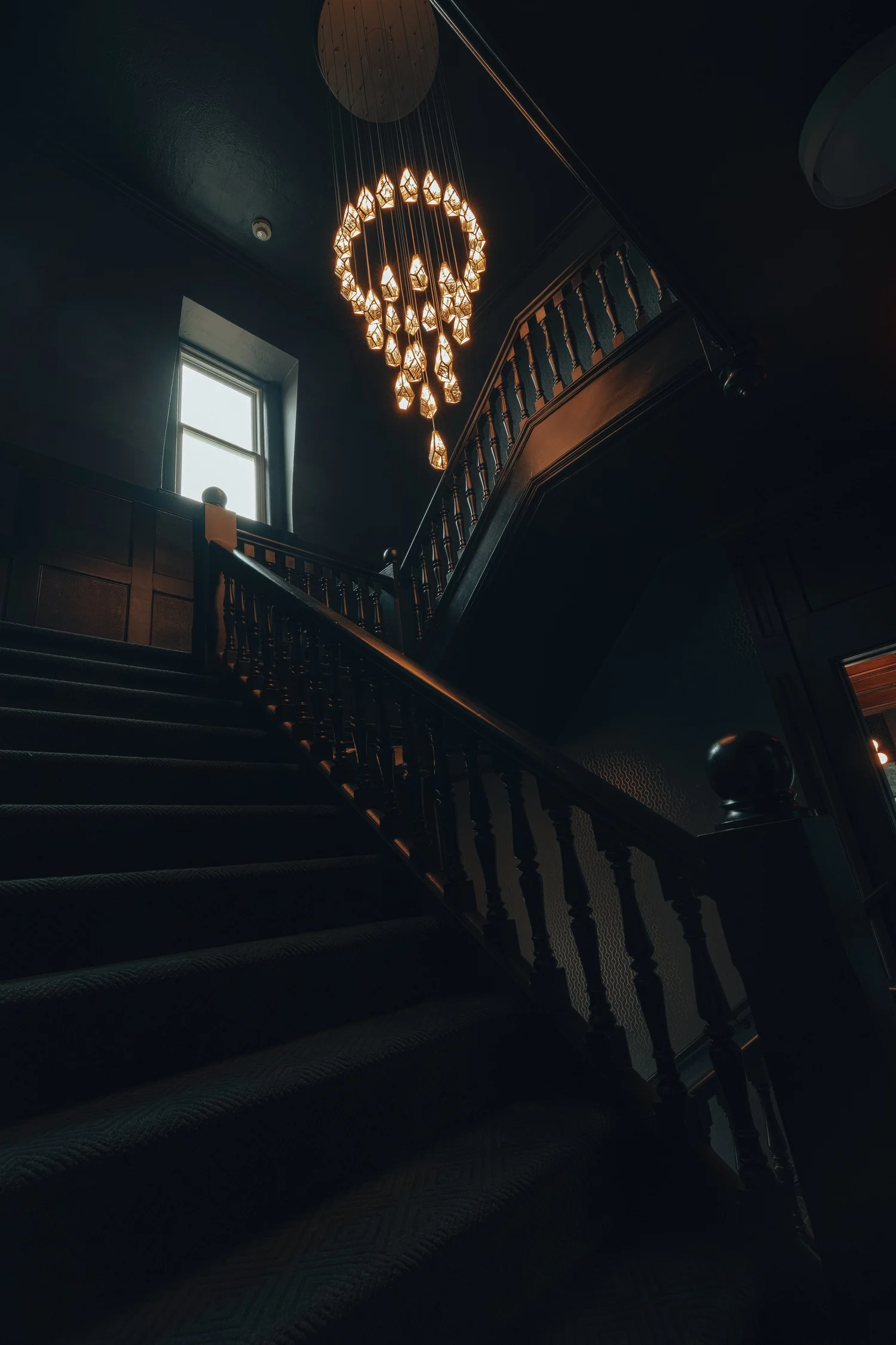 A staircase lit by a chandelier