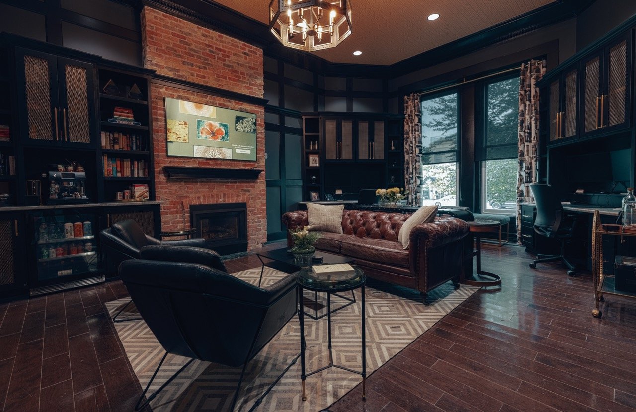 A sitting room with a tufted leather sofa and bookshelves