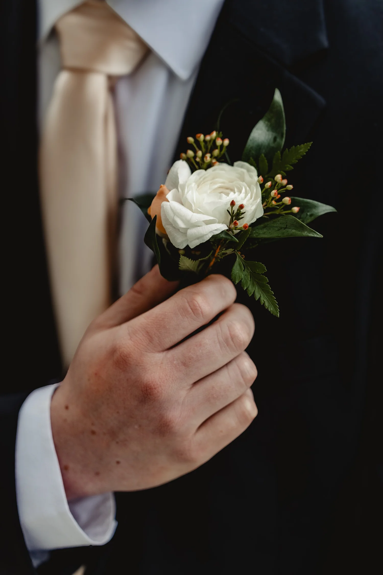A white rose boutonniere being pinned on