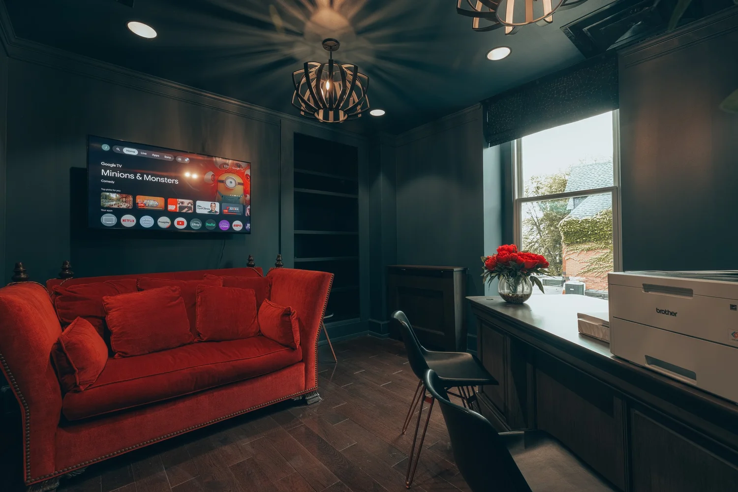 A red velvet sofa beneath a wall screen