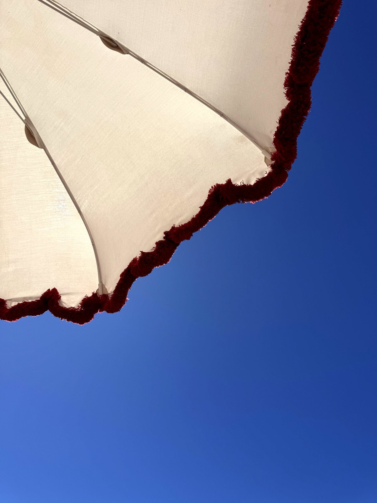Fringed beach umbrella against a blue sky