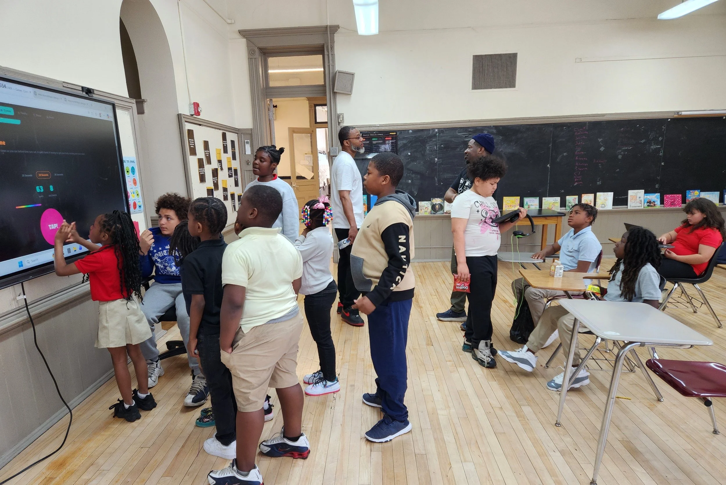 Students standing and engaging with an interactive lesson on a smartboard