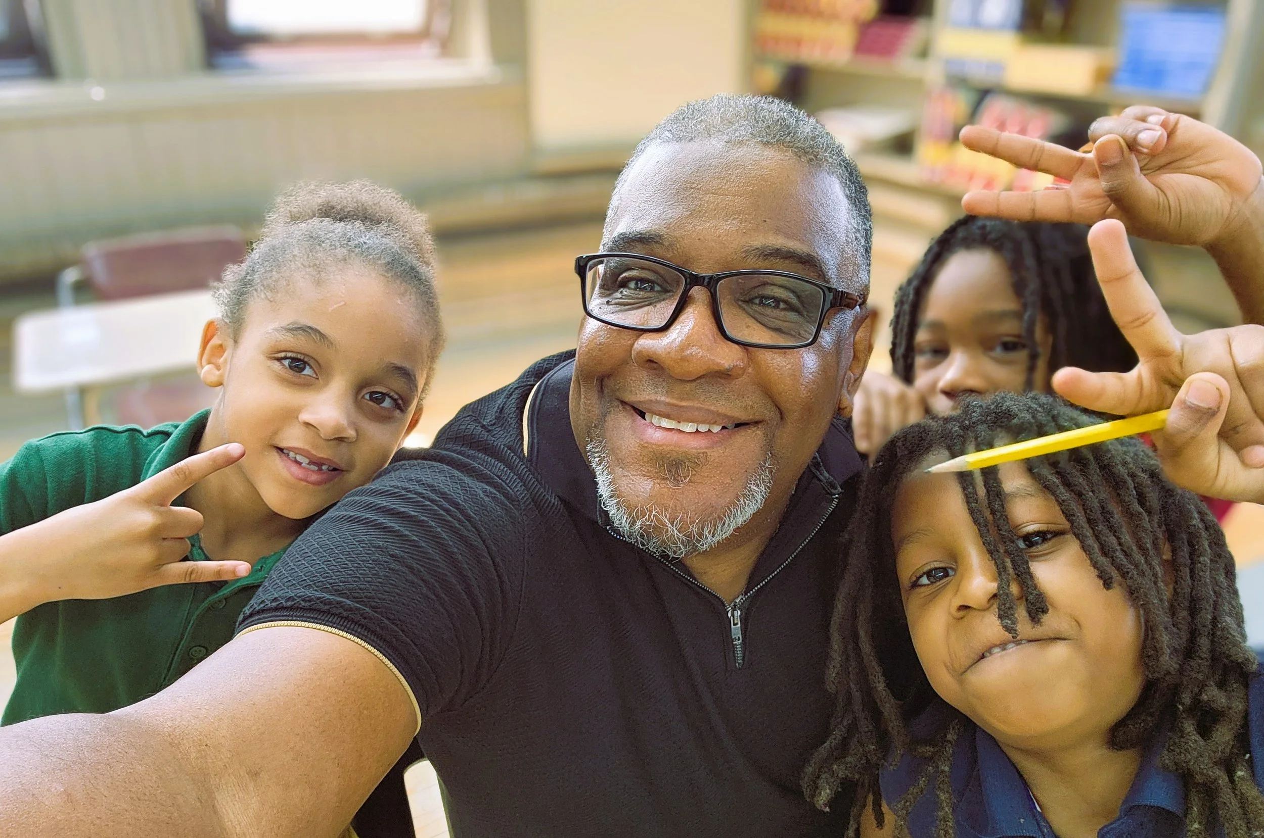 A staff member taking a photo with students in the classroom