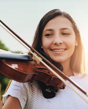 A girl smiling behind a violin