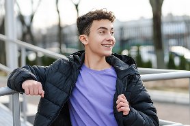A boy leaning back against a railing, smiling