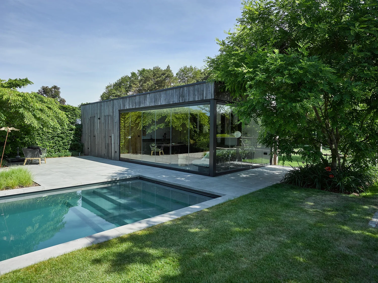 Tuin met zwembad en poolhouse met glazen wand in Zutendaal